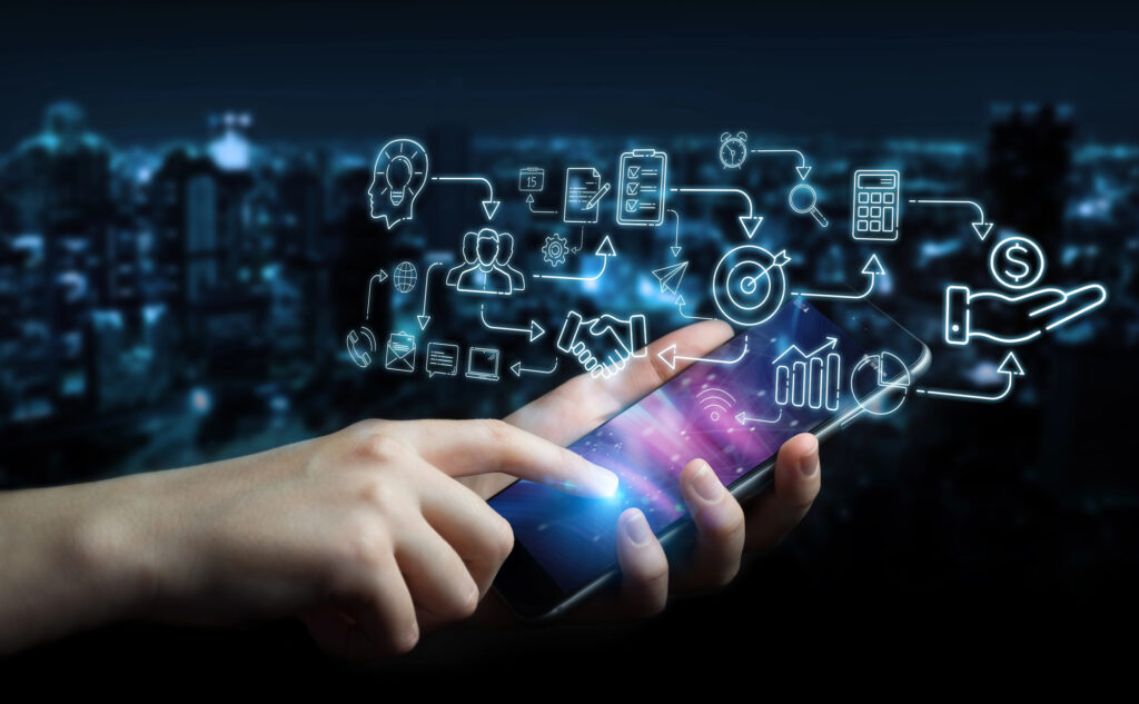 Hand tippt auf Mobiltelefon, verschiedene blau leuchtende Symbole, dunkler Hintergrund