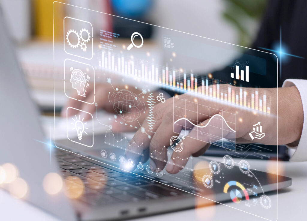 Hand über Laptoptastatur, überlagert von digitaler Anzeige mit verschiedenen Graphen und Symbolen