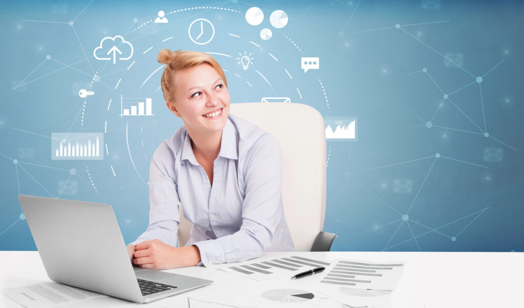 lächelnde Frau am Schreibtisch, offener Laptop, im Hintergrund verschiedene digitale Symbole