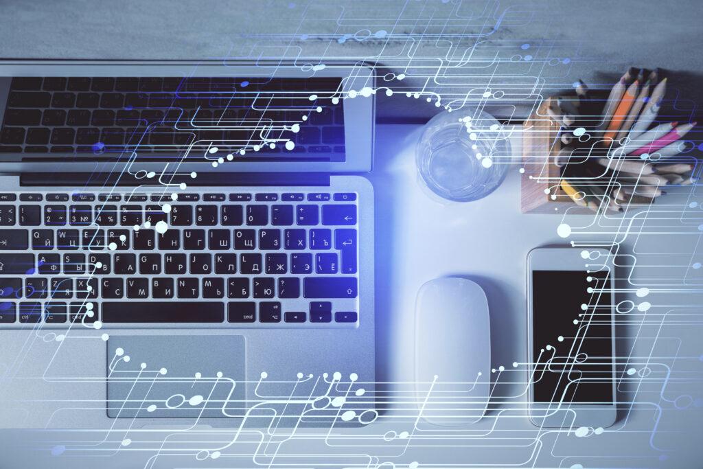 Schreibtisch Ansicht von oben mit Laptop, Maus, Smartphone, Wasserglas, Behälter mit Buntstiften, im Vordergrund digitale Datenwolke